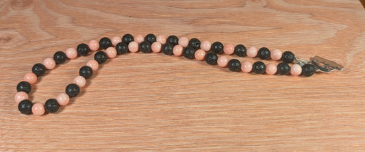 Necklace with pink and black beads on a wooden surface