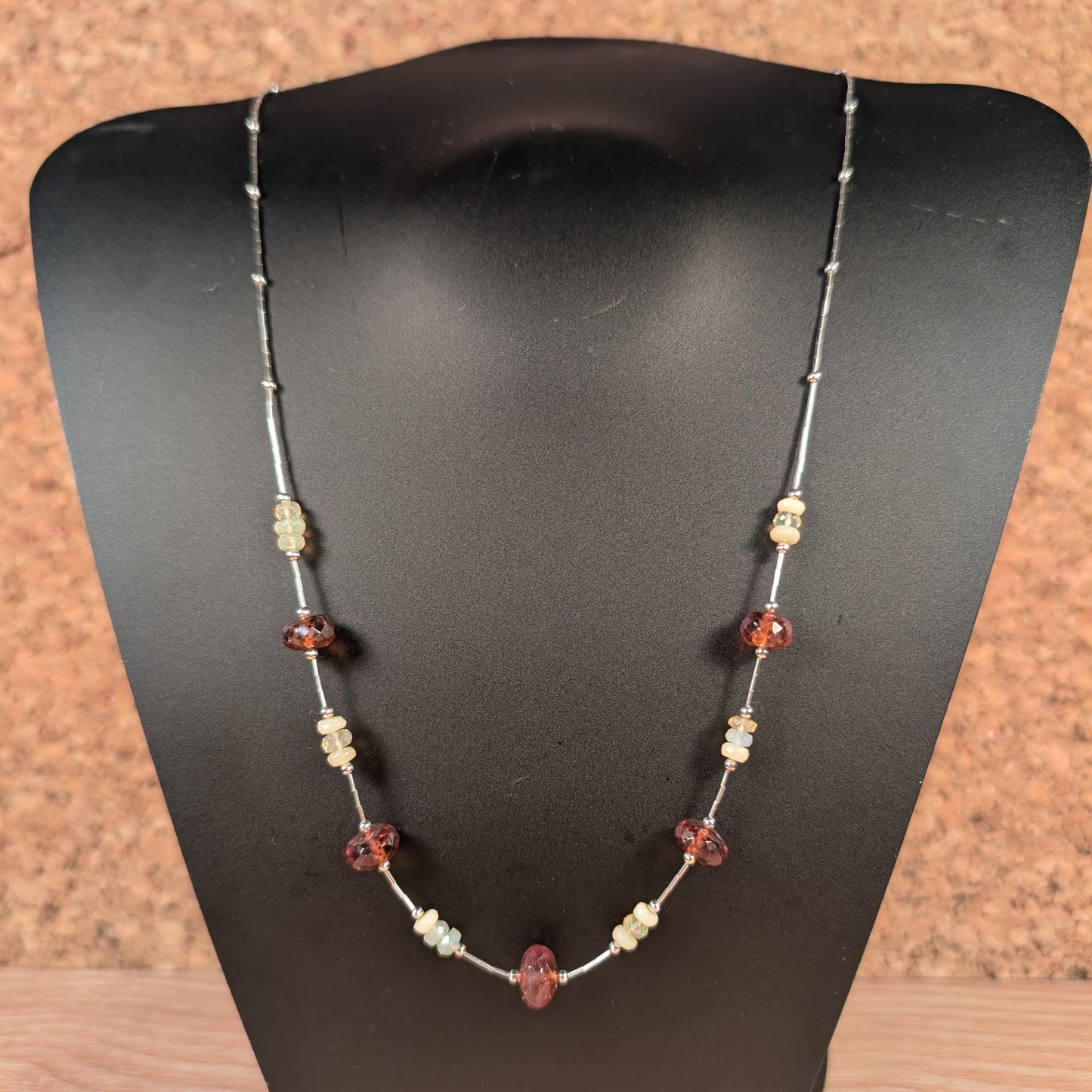 Necklace with beads on a black mannequin bust against a brown background