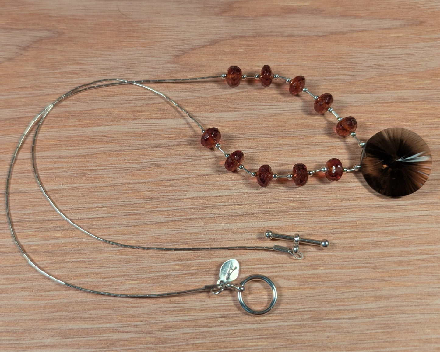 Necklace with red beads and silver clasp on a wooden surface