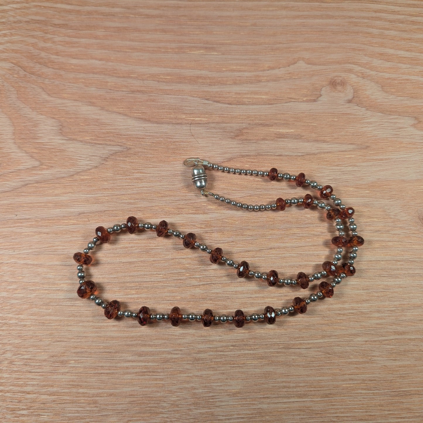 Necklace with brown and silver beads on a wooden surface