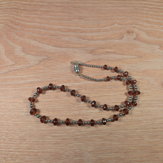 Necklace with brown and silver beads on a wooden surface
