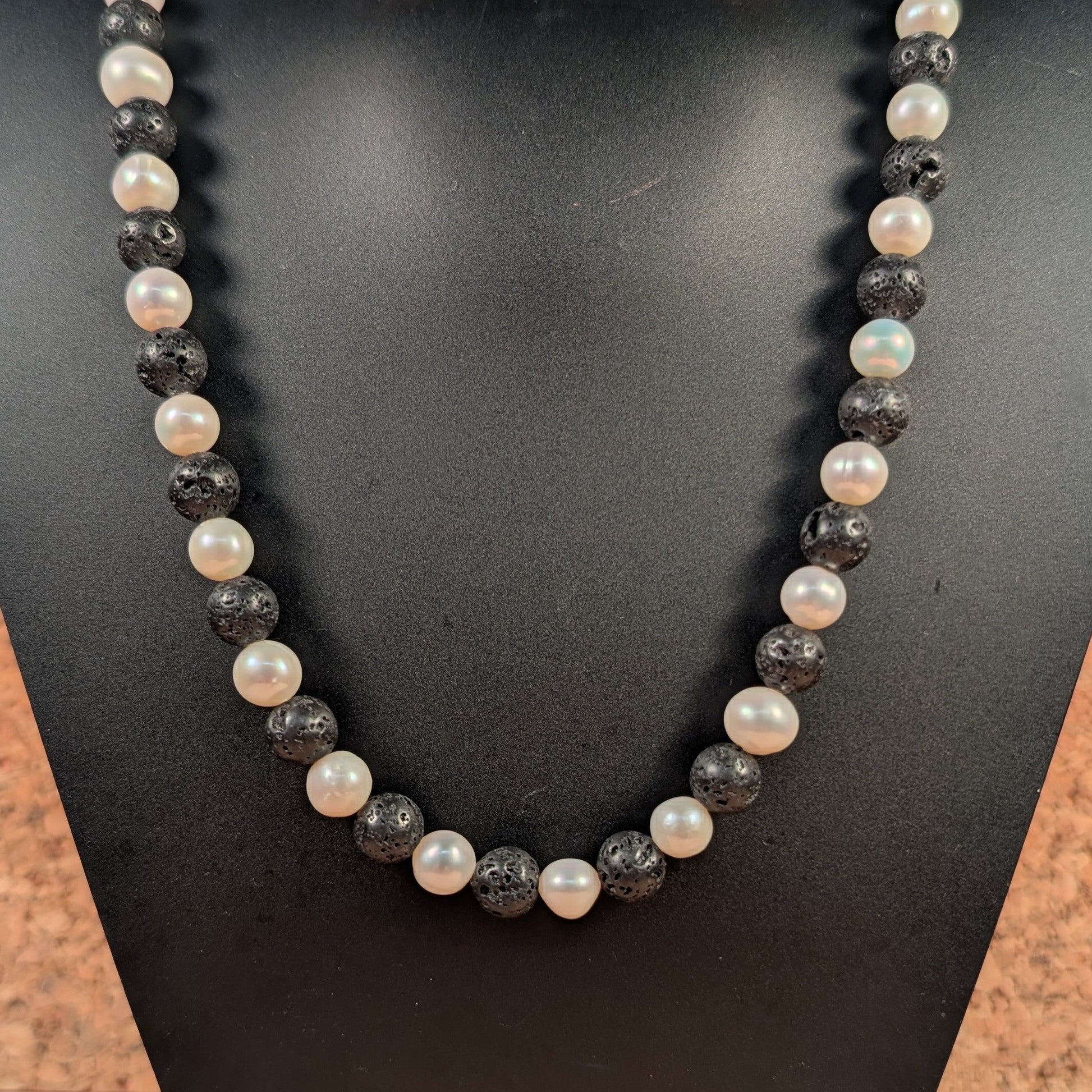 Necklace with black and white beads on a black mannequin bust.