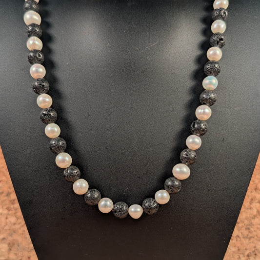 Necklace with black and white beads on a black mannequin bust.