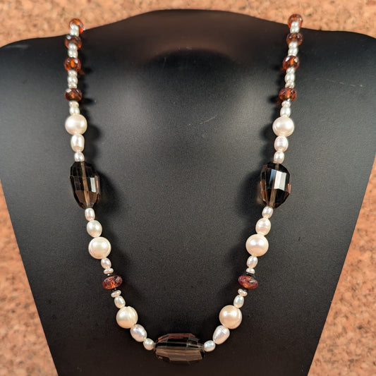 Necklace with pearls and brown beads on a black mannequin bust against a wooden background