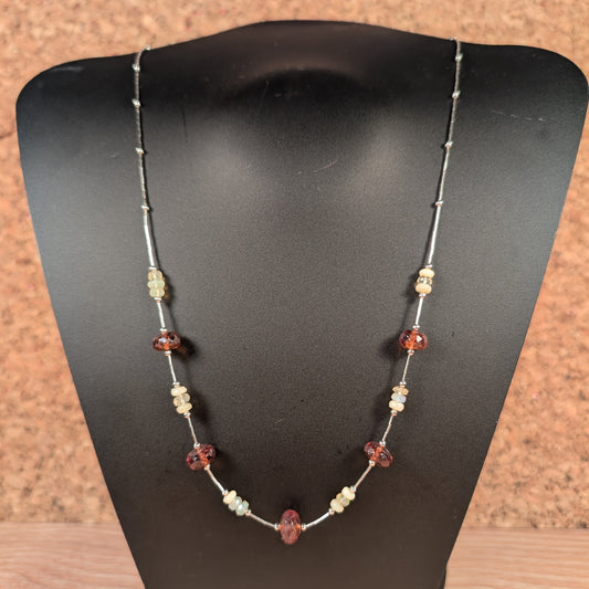 Necklace with beads on a black mannequin bust against a brown background