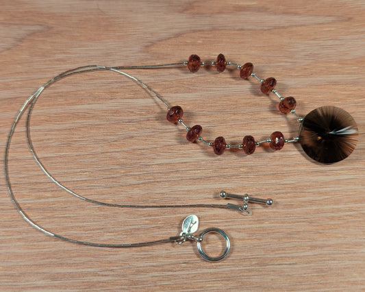 Necklace with red beads and silver clasp on a wooden surface