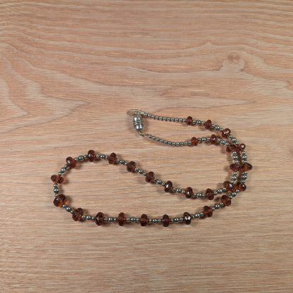 Necklace with brown and silver beads on a wooden surface