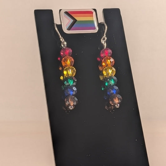 Rainbow beaded earrings on a black card with a rainbow flag design.