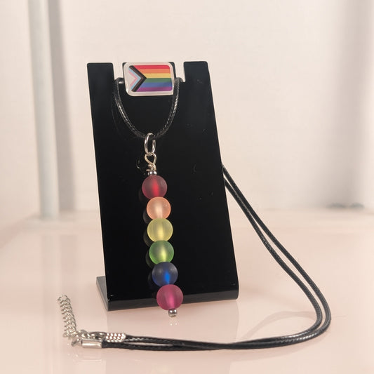 Necklace with rainbow beads on a black stand with a white background